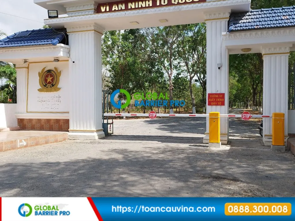 Cổng chính với barie ngang dài gắn hai biển STOP và hai trụ barie vàng